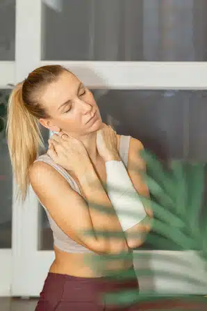 Beautiful young woman practicing sports at home and getting neck pain from exercising