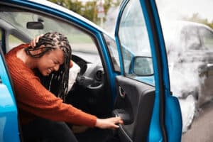 woman getting out of her car after accident experiencing whiplash symptoms