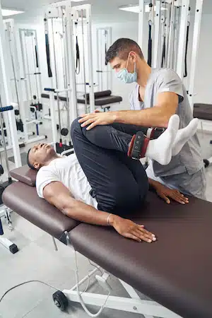 Professional physical therapist rehabilitating male patient legs
