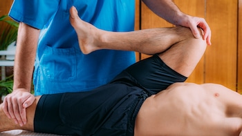 chiropractor making adjustments on patient's leg to check on post accident fractures or injury