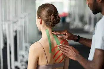 close up of a physiotherapist applying kinesio tape to his client's back