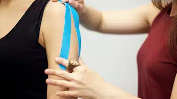 kinesiology taping treatment with blue tape on female patient's arm