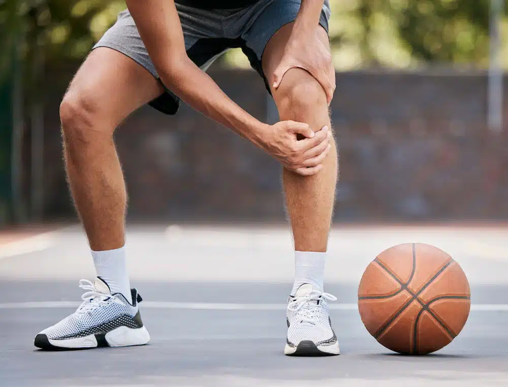 man acquiring sports injury while playing basketball