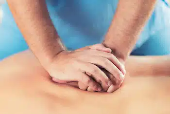 chiropractor cracking man's back during manual therapy session 