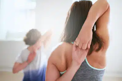 More Life Chiropractic | Woman doing a shoulder stretch with Improved Mobility from chiropractic treatment