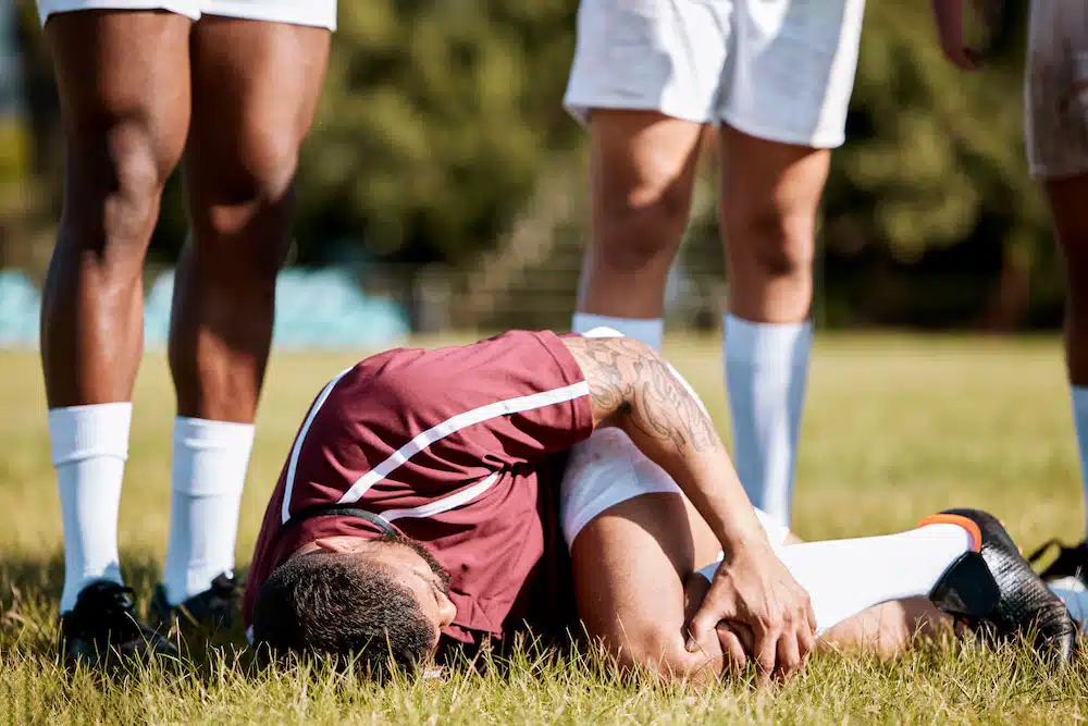 soccer athlete experiencing pain from knee injury during the game