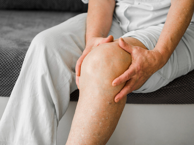 elderly man holding his leg because of pain