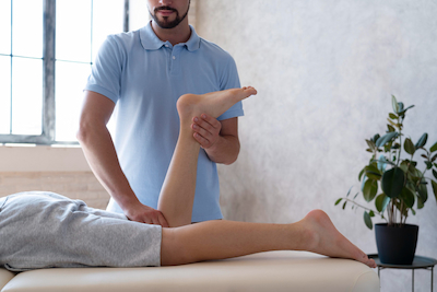 chiropractor doing leg stretches on patient with leg pain