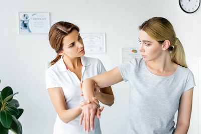 chiropractor treating female patient with elbow pain