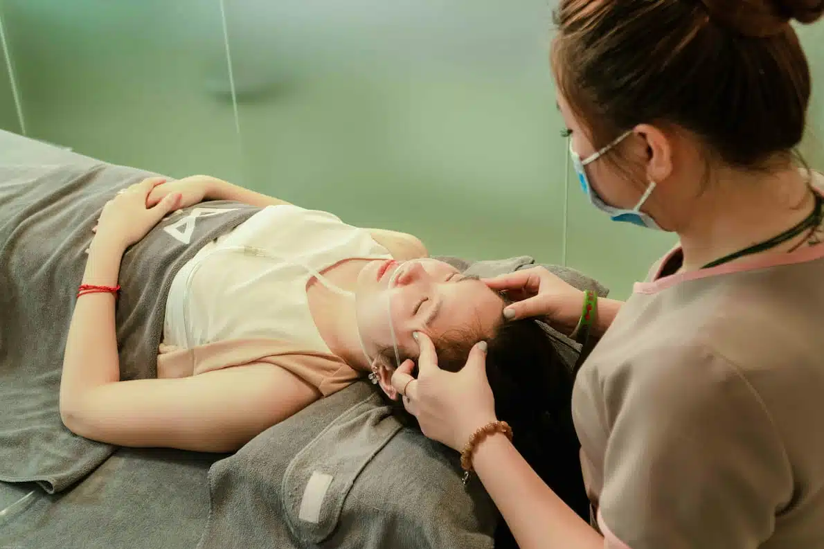 A-Woman-Lying-Down-while-Having-Her-Head-Massage-by-a-Therapist