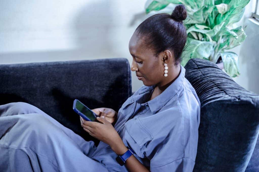 Woman using smartphone with forward head posture, illustrating a common trigger for cervicogenic headaches.