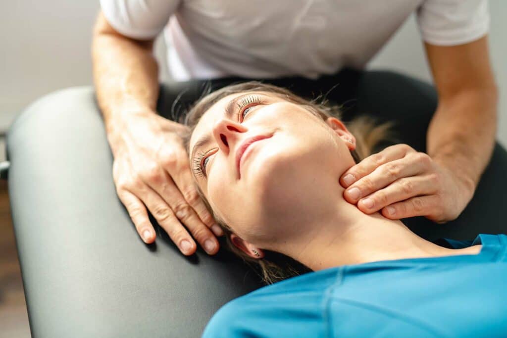 A chiropractor manually adjusting and supporting the neck of a female patient.