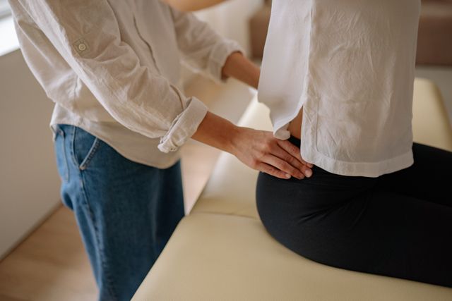 A chiropractor examining a patient's lower back and hip alignment on a treatment table.