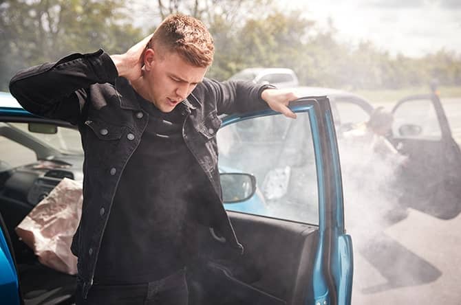 Driver holding neck in pain after a car accident needing auto injury treatment.